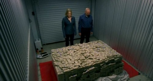 A man and woman are staring at a pile of money inside a self storage unit.
