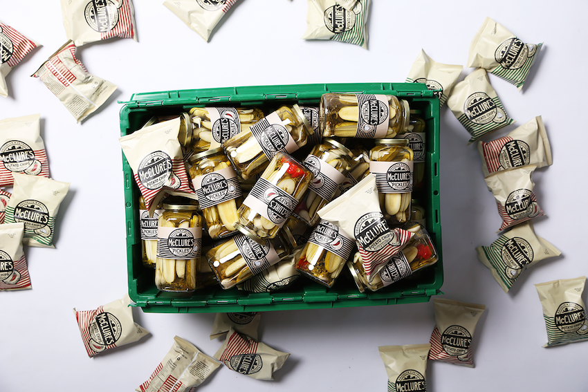 A green MakeSpace storage bin is packed full with jars of McClure's Pickles.