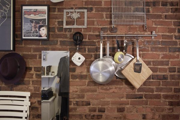 mary helen rowell's wall storage hangs bistro chairs, a mirror, picture frames, a camera, cooking tools, headphones, and more