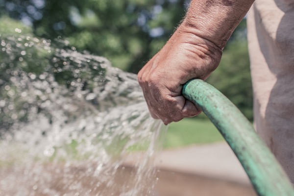 man holding a garden hose in his left hand