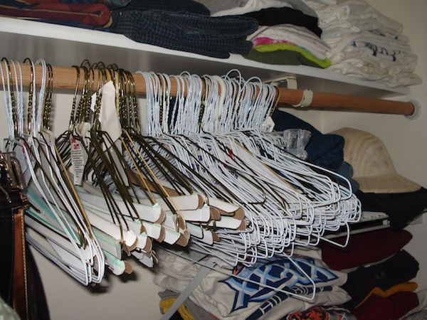 Old wire hangers are crammed together in a dimly lit closet