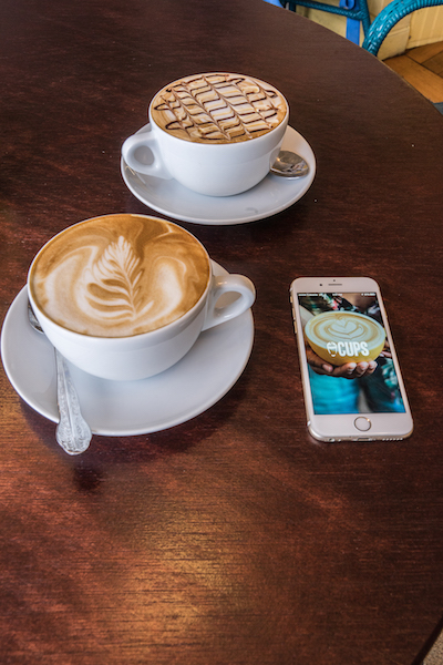 two delicious looking coffee drinks next to the app, Cups