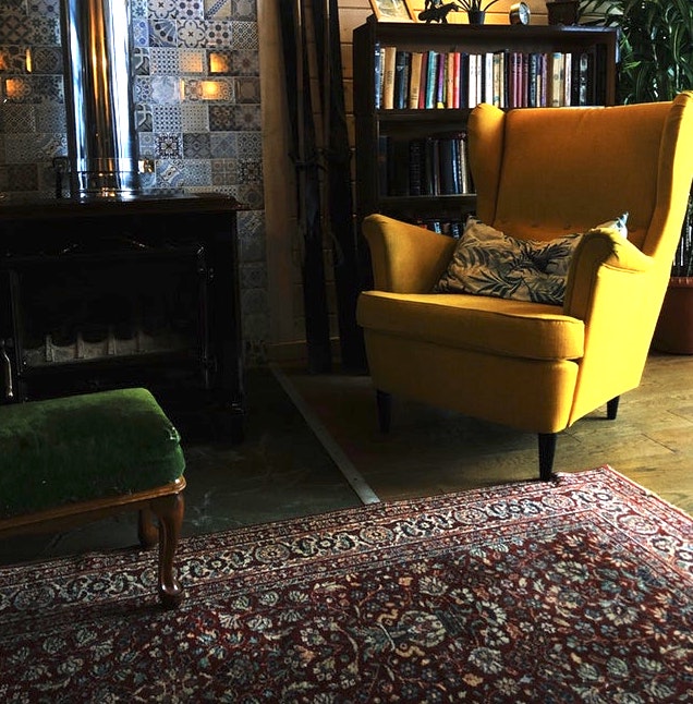 a bright yellow chaise on an ancient rug