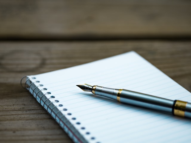 An ink pen laying on top of a journal.
