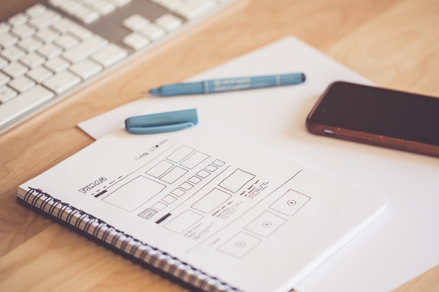 A notebook with a sketch, while a pen and a phone lay next to it.
