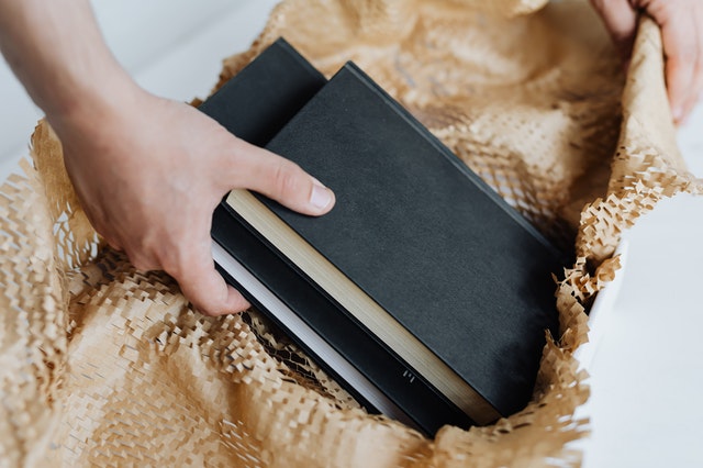 A pair of hands taking out books from a brown paper box