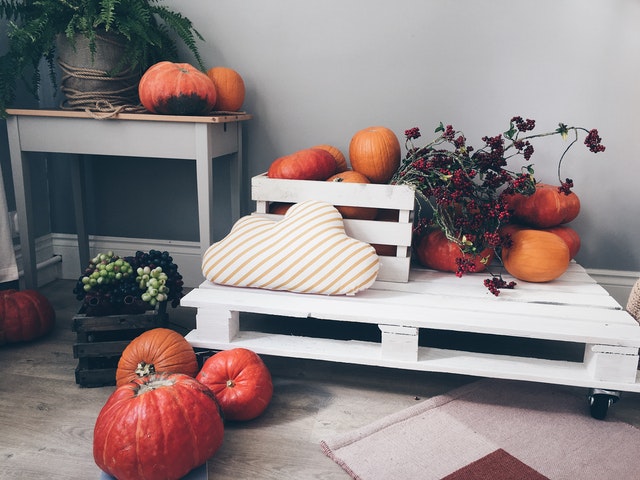 A few bright pumpkins surrounded by a crate of dried berries and flowers.