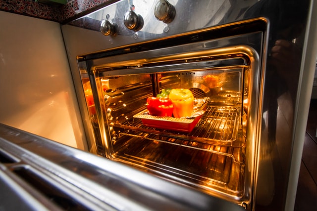 An open clean oven with food on a baking tray.