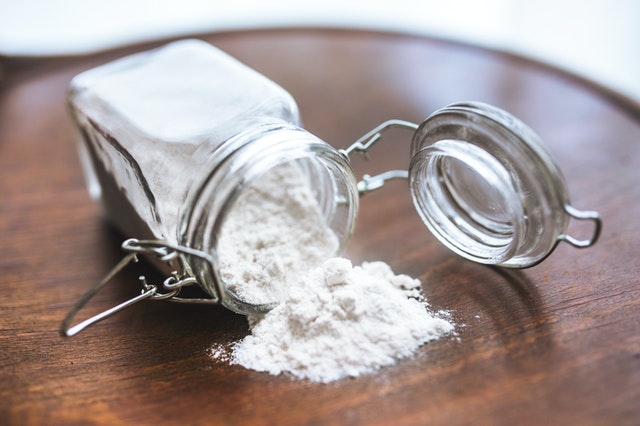 A bottle of baking soda against a wooden floor.