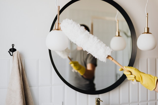 A hand wearing gloves cleaning a mirror